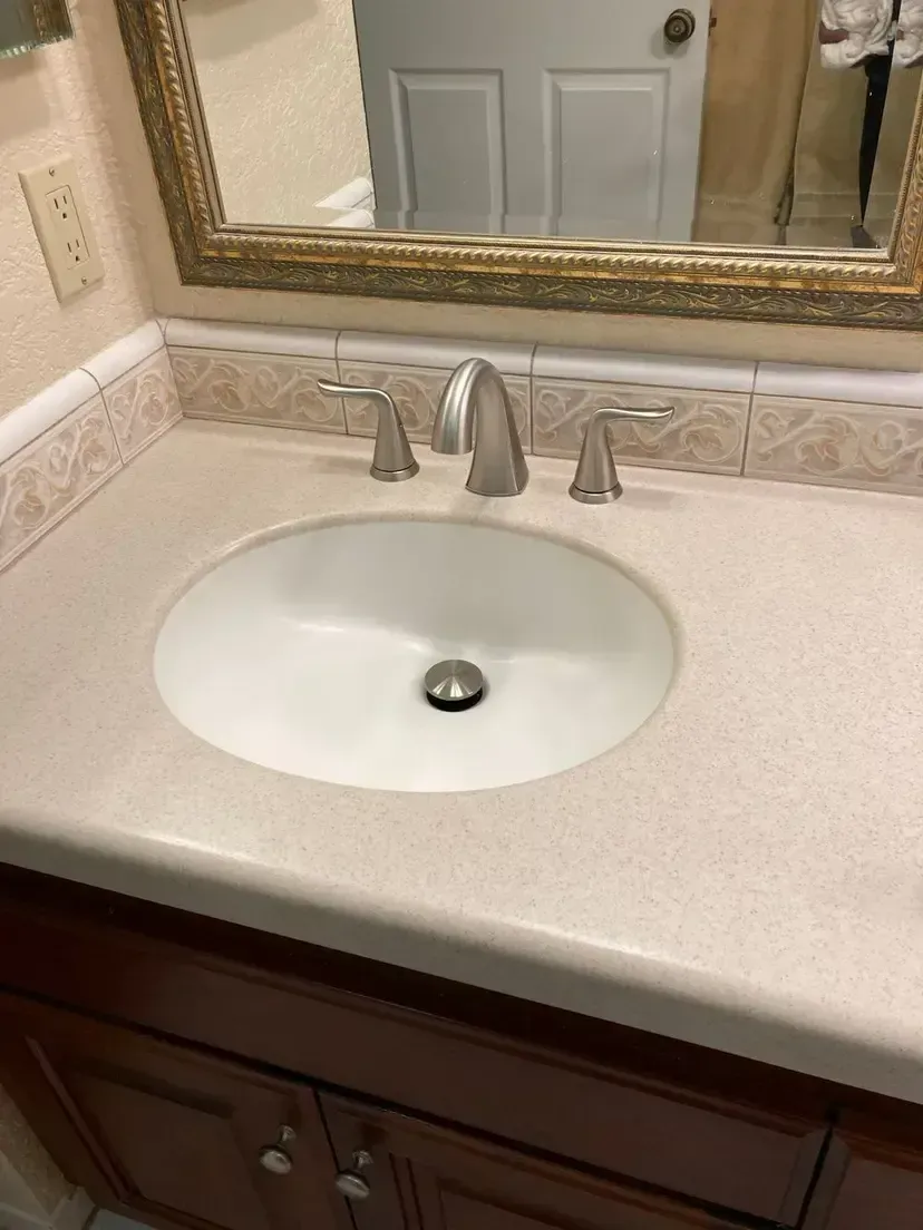 Bathroom sink with chrome faucet, oval basin, and beige countertop.