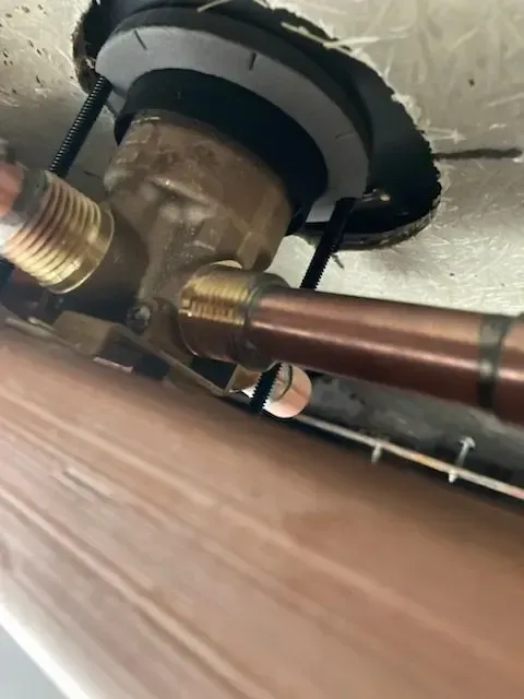 Copper pipes connected to a brass valve in a wall.