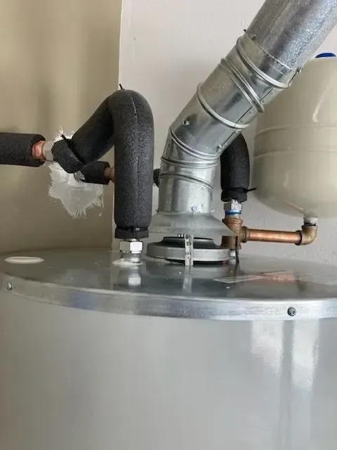 Water heater with insulated pipes and vent.