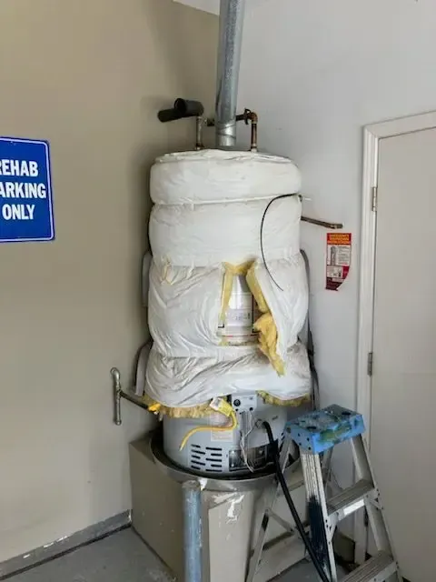 Water heater with insulation, in a garage. A blue 