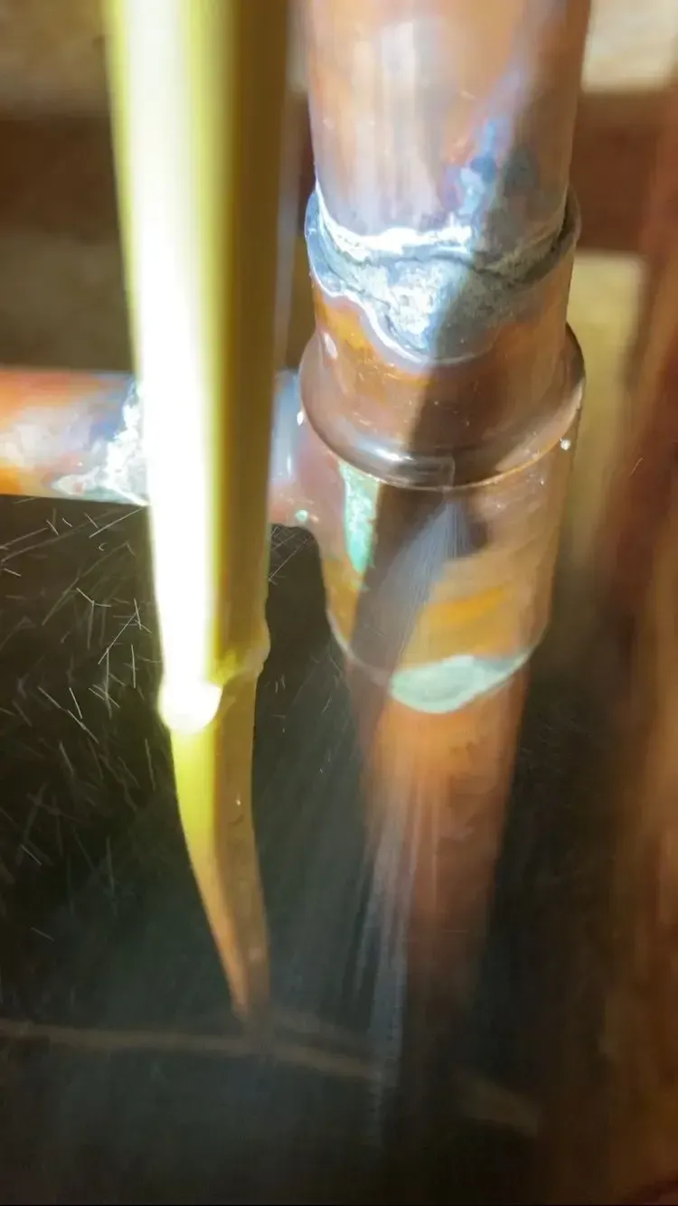 Copper pipe with greenish corrosion and a solder joint, possibly leaking.