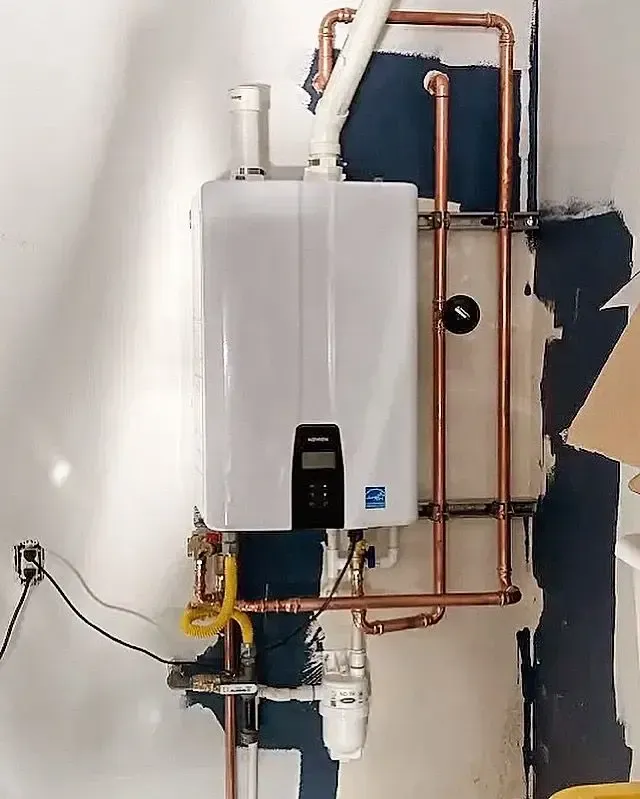 White tankless water heater installed on a wall with copper pipes. Yellow gas line.
