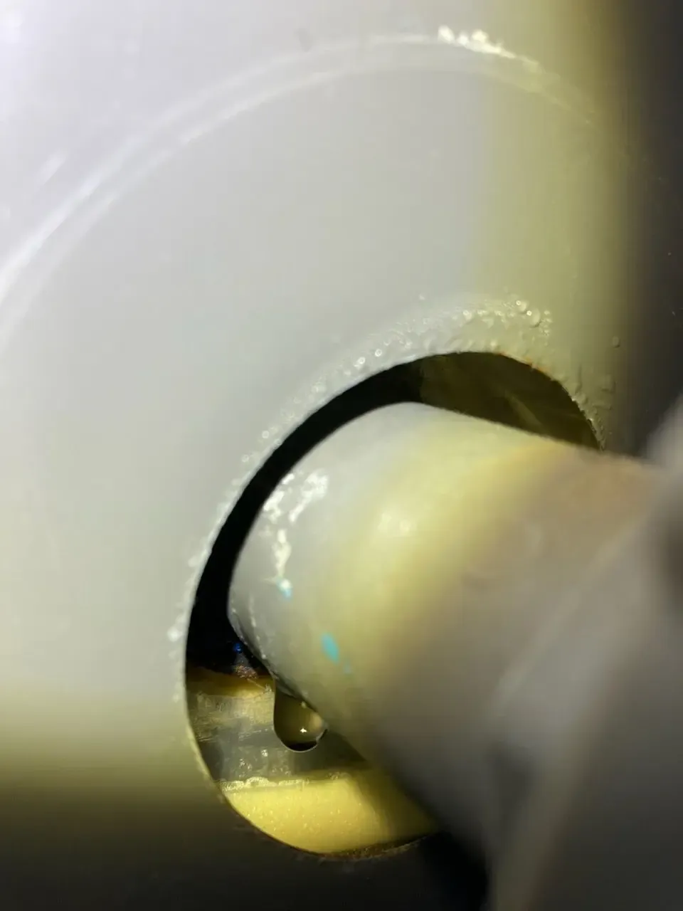 Close-up view of a light gray cylindrical object with a curved opening, showing a yellow-toned mechanism inside.