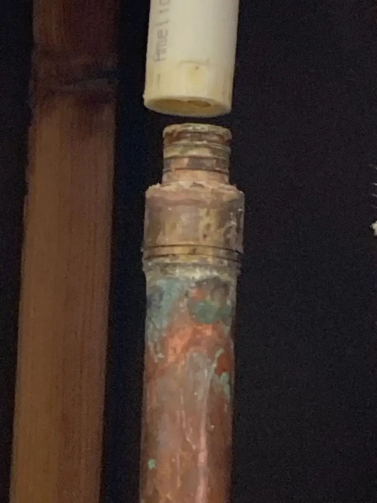 Copper pipe fitting with threaded top, PVC pipe above, and copper pipe to the left.