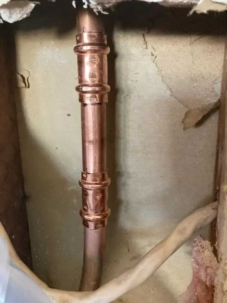 Copper plumbing pipes installed in a wall.