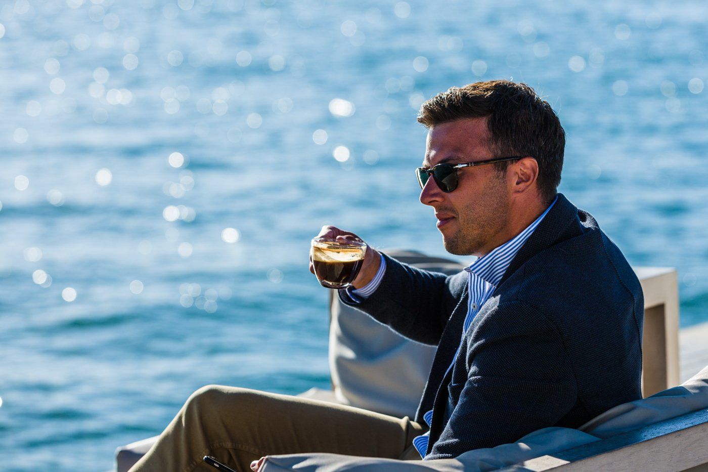 Samuel Cise, founder of Saxon Insurance Brokers is sitting on a boat holding a cup of coffee .