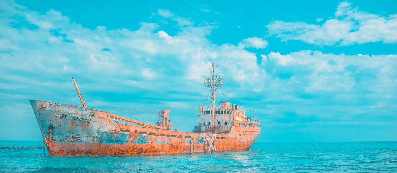an old ship is floating on top of a large body of water .