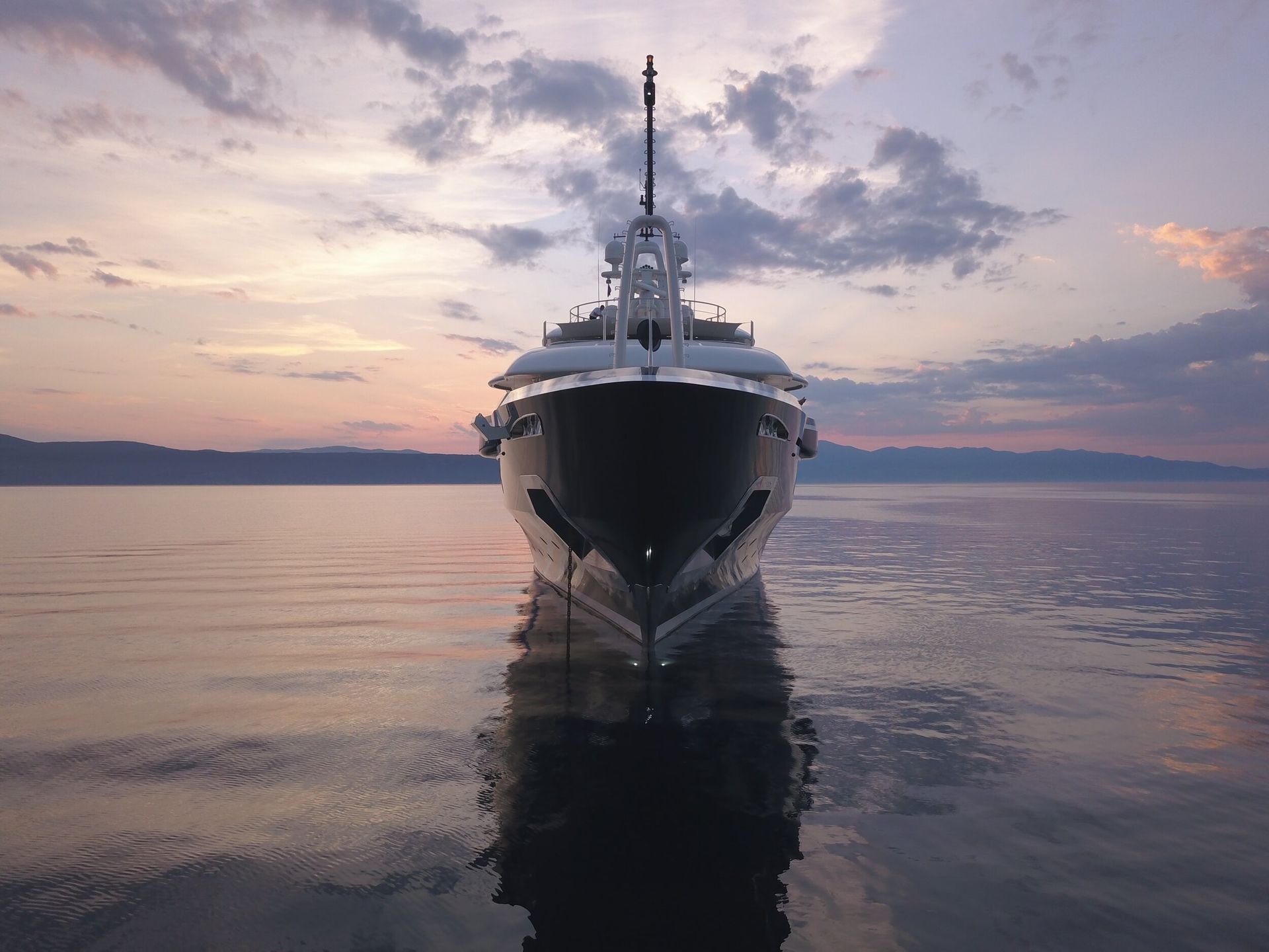 a large yacht is docked in the water at sunset .
