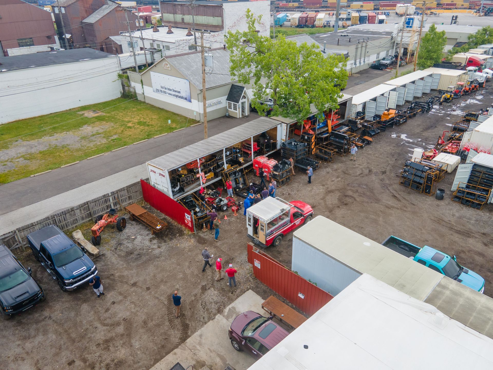 Aerial view of outdoor work site; several people around open container, trucks and equipment.