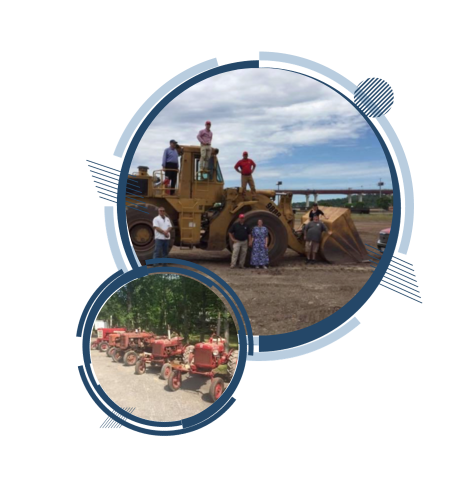 People standing near heavy machinery and a row of small tractors.