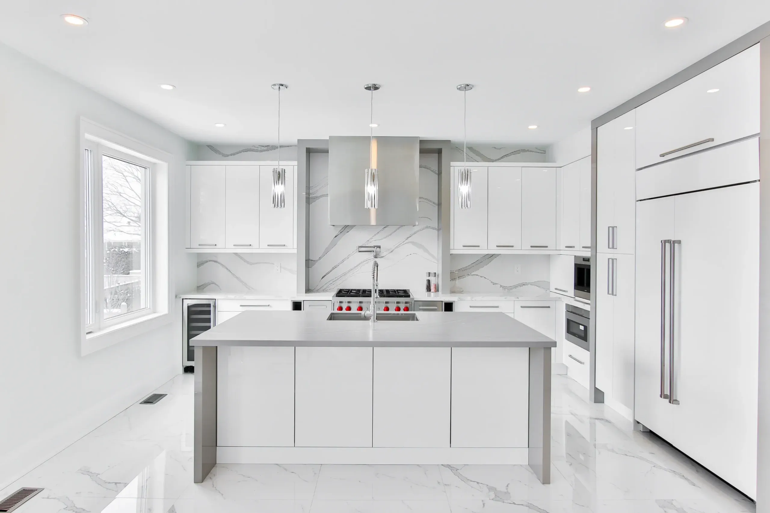Modern white kitchen with island, marble backsplash, stainless steel appliances.