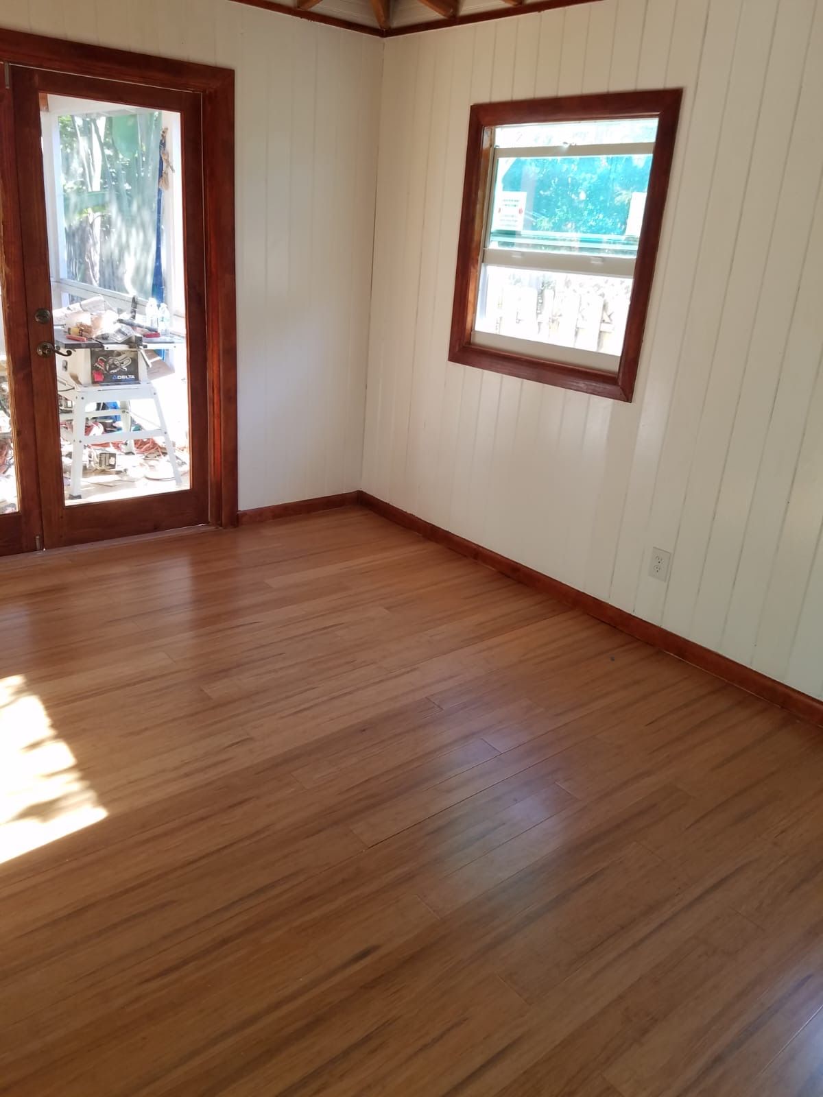 Empty room with hardwood floors, white walls, and wooden trim around doors and windows.