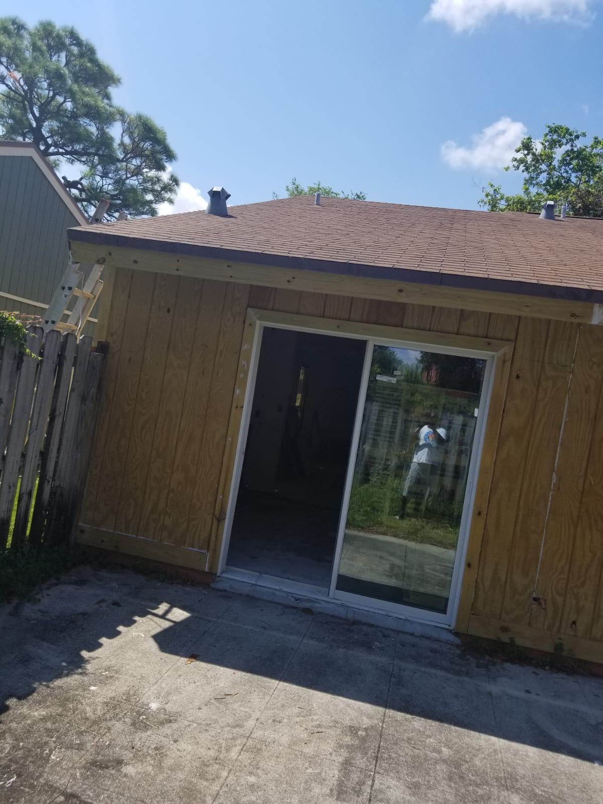 Small building with open sliding glass door; brown roof, light brown siding.