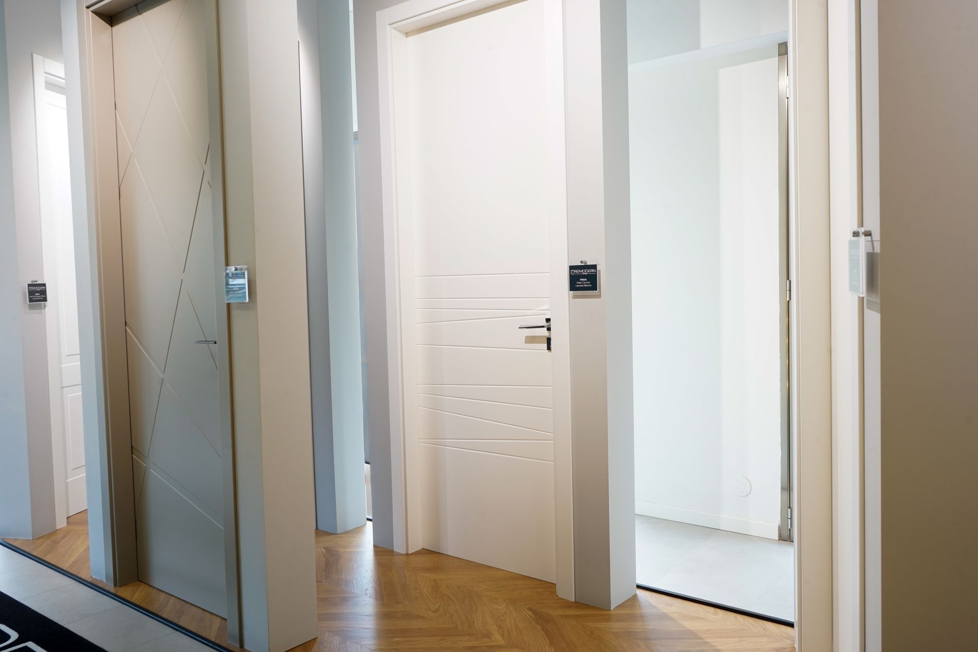 Luminoso corridoio con porte bianche e pareti a specchio, che mostra un interno moderno con pavimento in legno