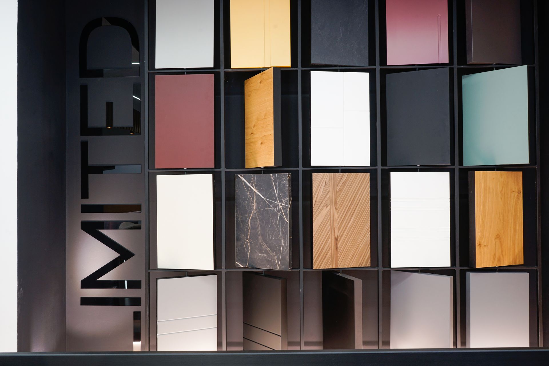 Esposizione IMTER di pannelli quadrati colorati e texture in uno showroom moderno