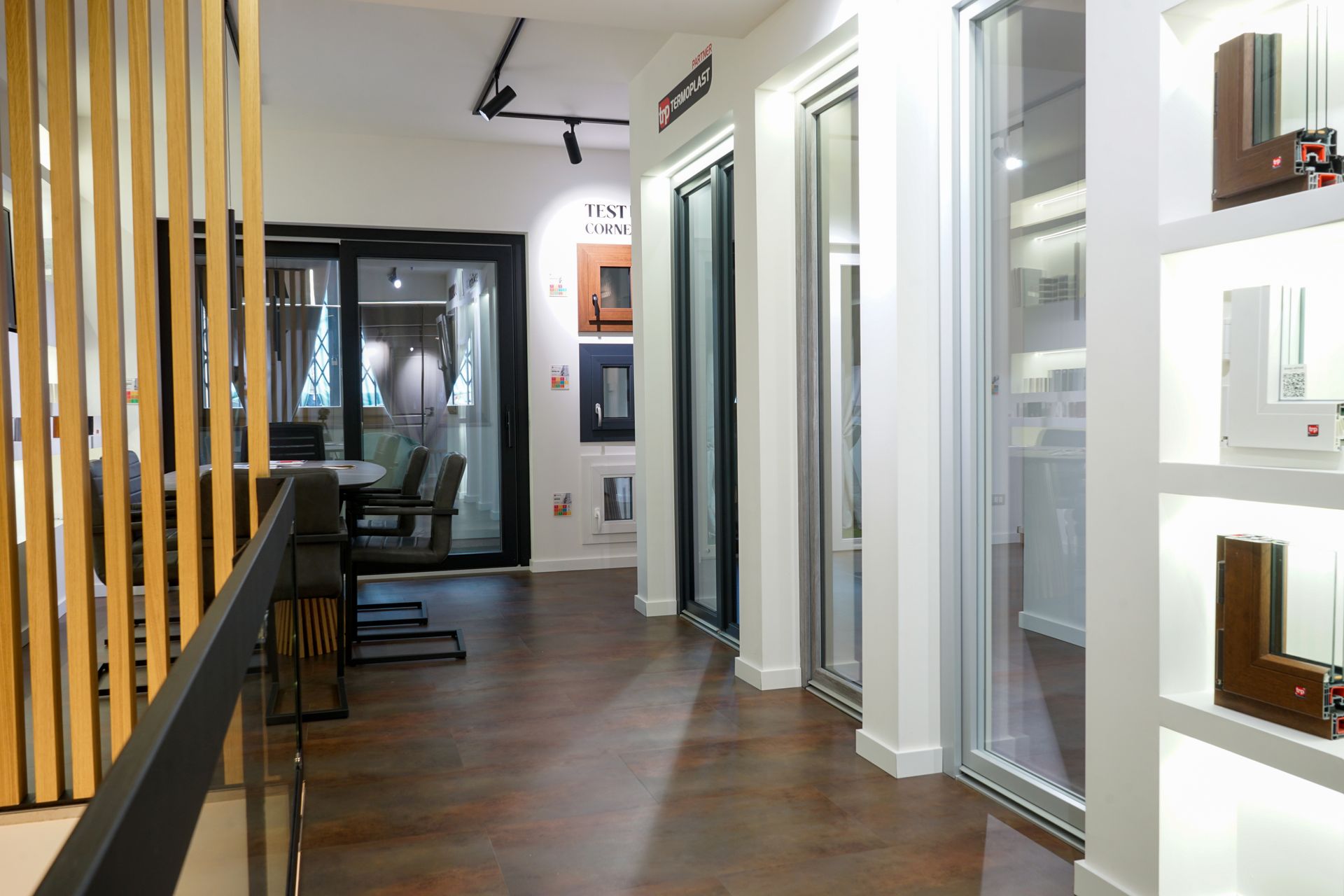 Ingresso moderno con pavimento in legno, porte in vetro e listelli verticali in legno accanto alla zona pranzo