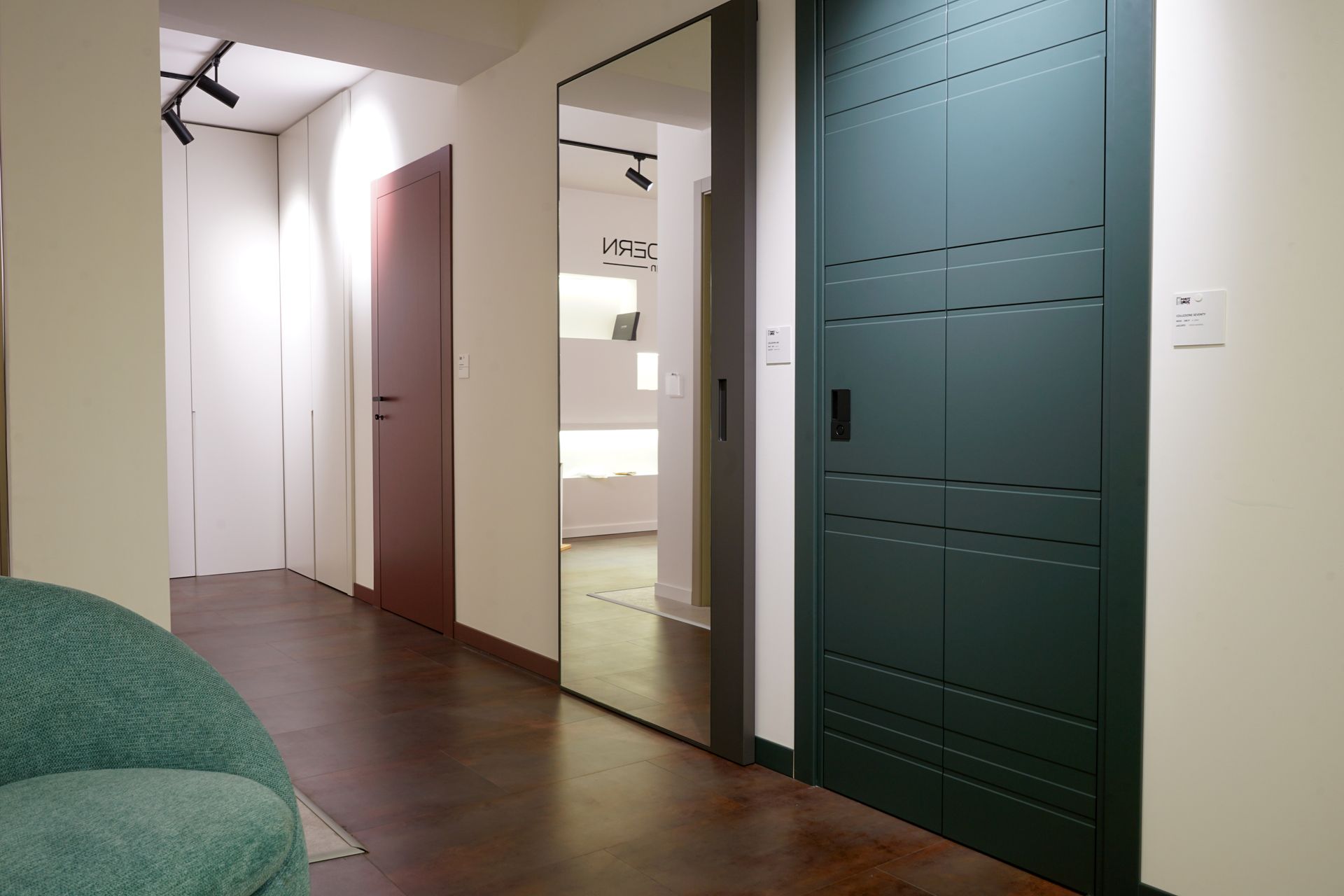 Ingresso moderno con pareti bianche, pavimento in legno scuro e porte colorate, tra cui una porta di armadio color verde acqua in primo piano