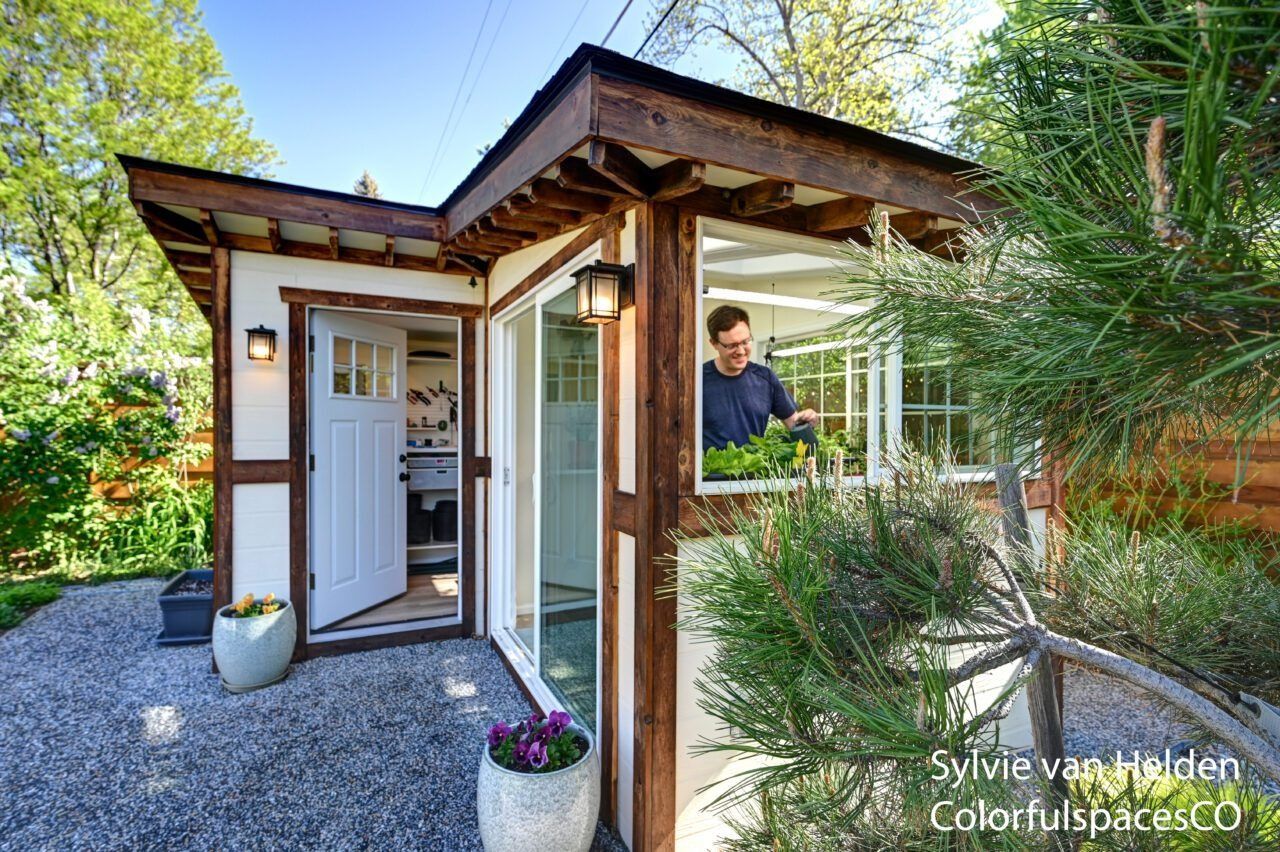 Modern house entrance with wood trim, white door, gravel path, and a person standing inside the doorway
