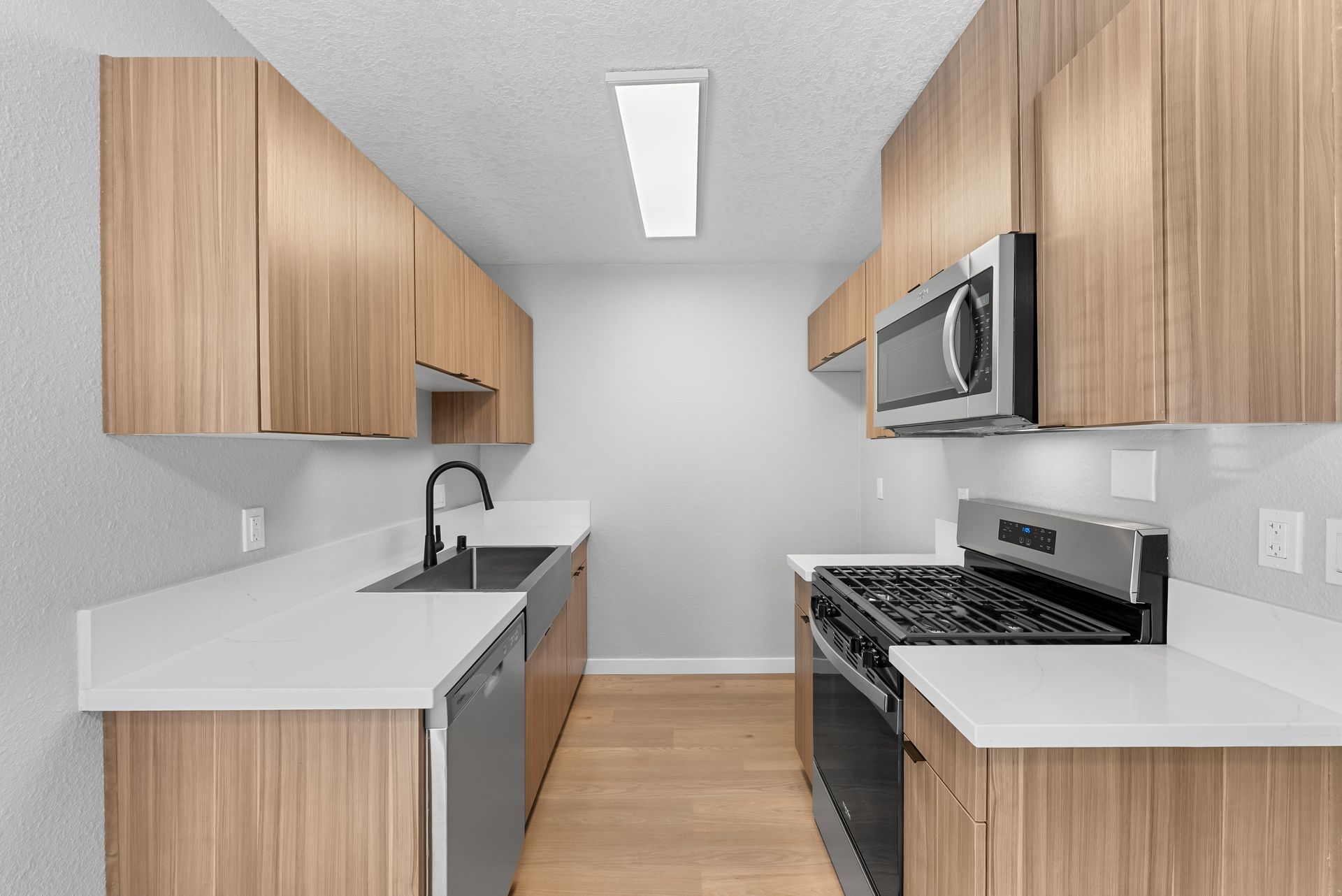 apartment kitchen with sink, microwave, stove, and dishwasher with overhead light