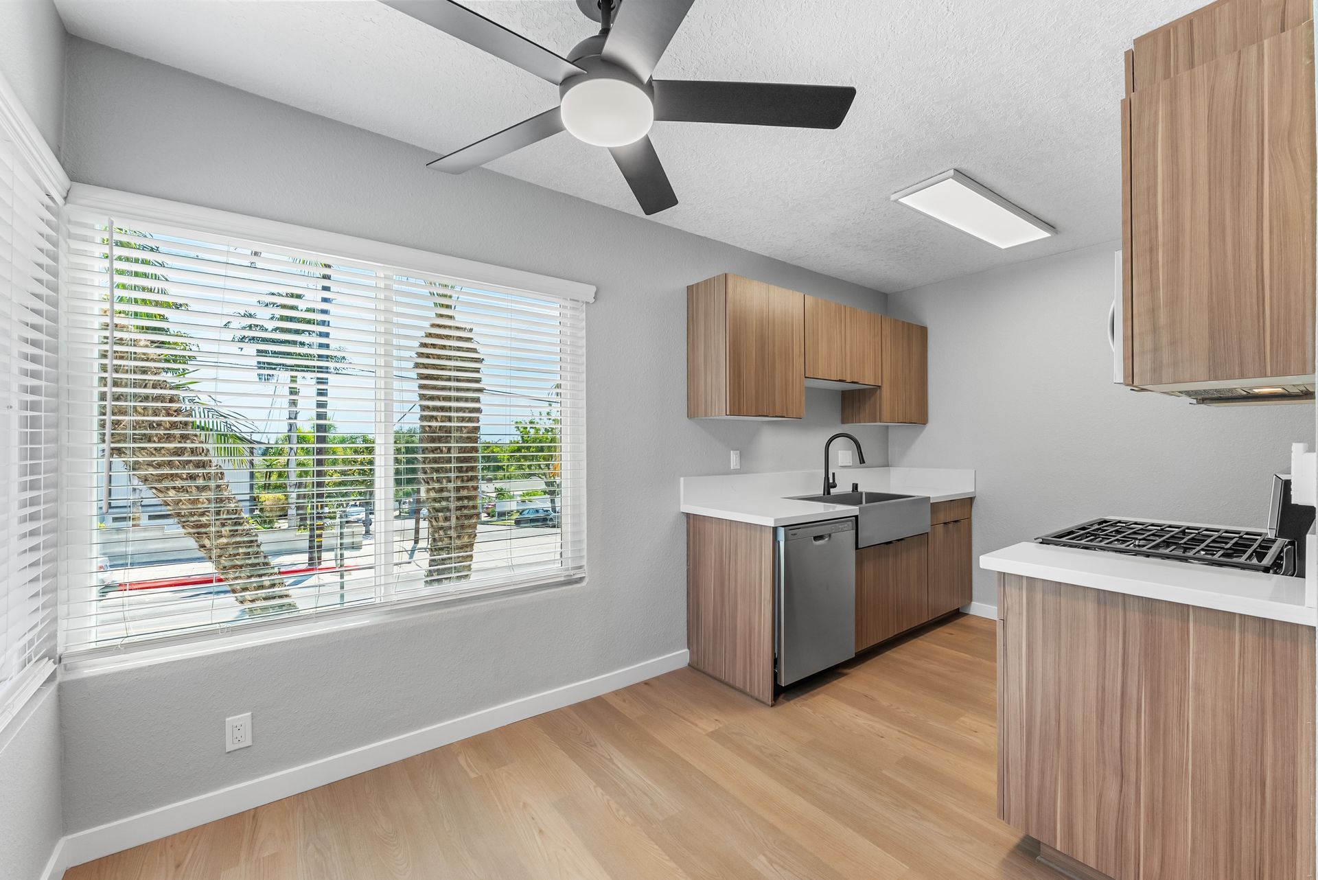 apartment kitchen with dishwasher, sink, and overhead fan next to a large window