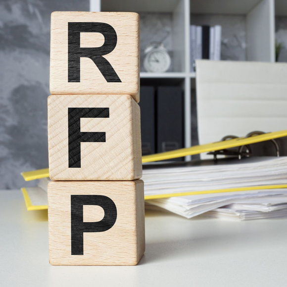 Wooden blocks stacked vertically with letters R, F, and P on a desk in an office setting
