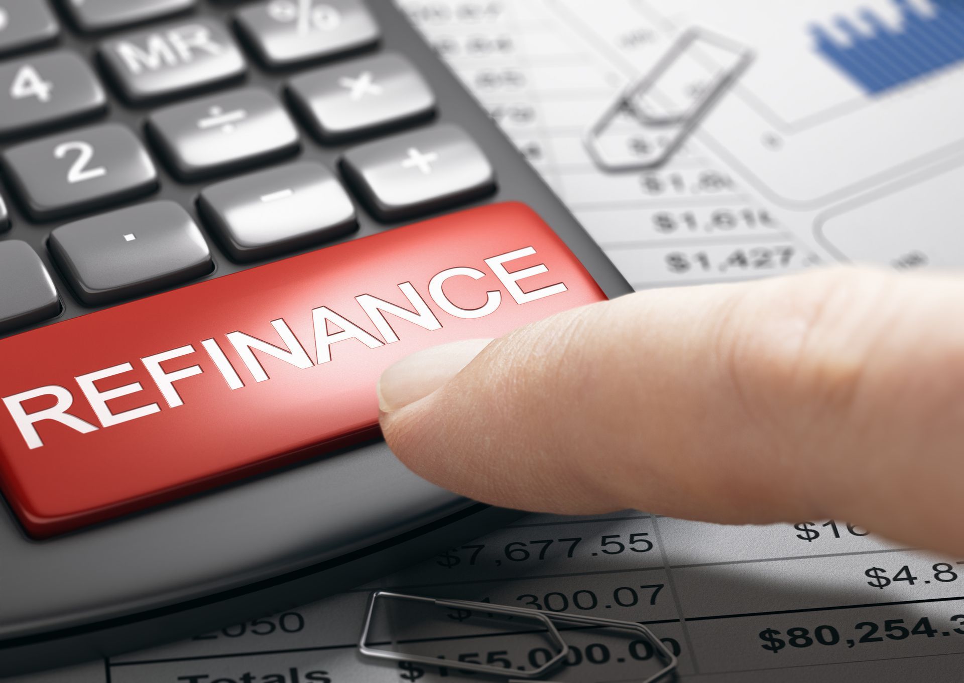 Finger pressing refinance button on calculator, representing refinances and mortgage planning. 