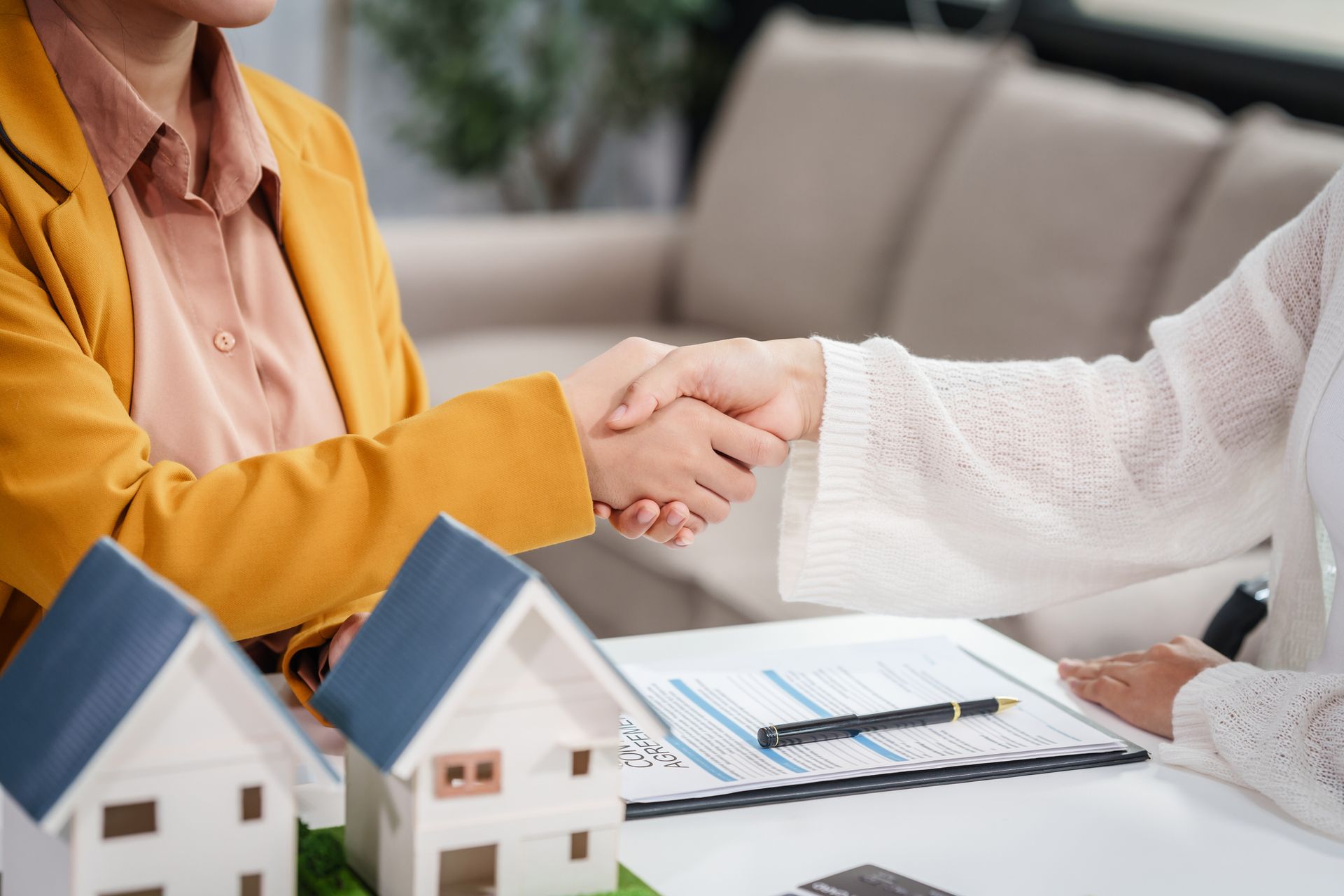 Escrow company agent shaking hands with clients during home purchase contract discussion.