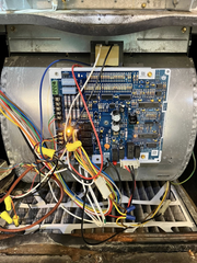 Open electronic control board with multicolored wires inside a metal machine cabinet
