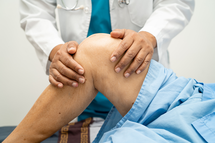 Doctor examining a patient’s bent knee in a clinic