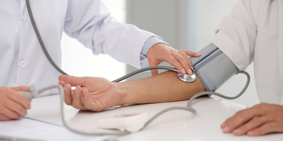 Doctor taking blood pressure with cuff on patient’s arm in a clinical setting