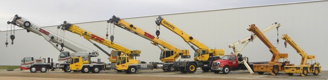 Five yellow tow trucks with extended boom arms lined up in a row on a lot