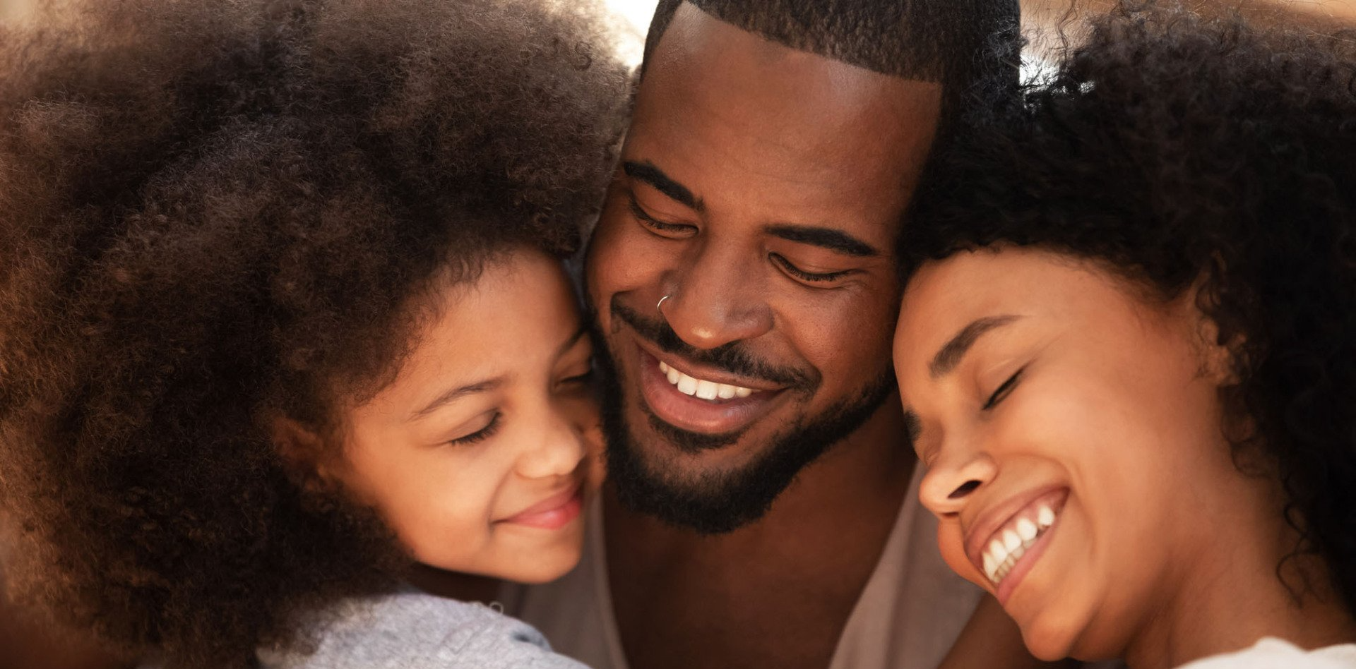 Three smiling people with their heads close together in a warm, intimate close-up