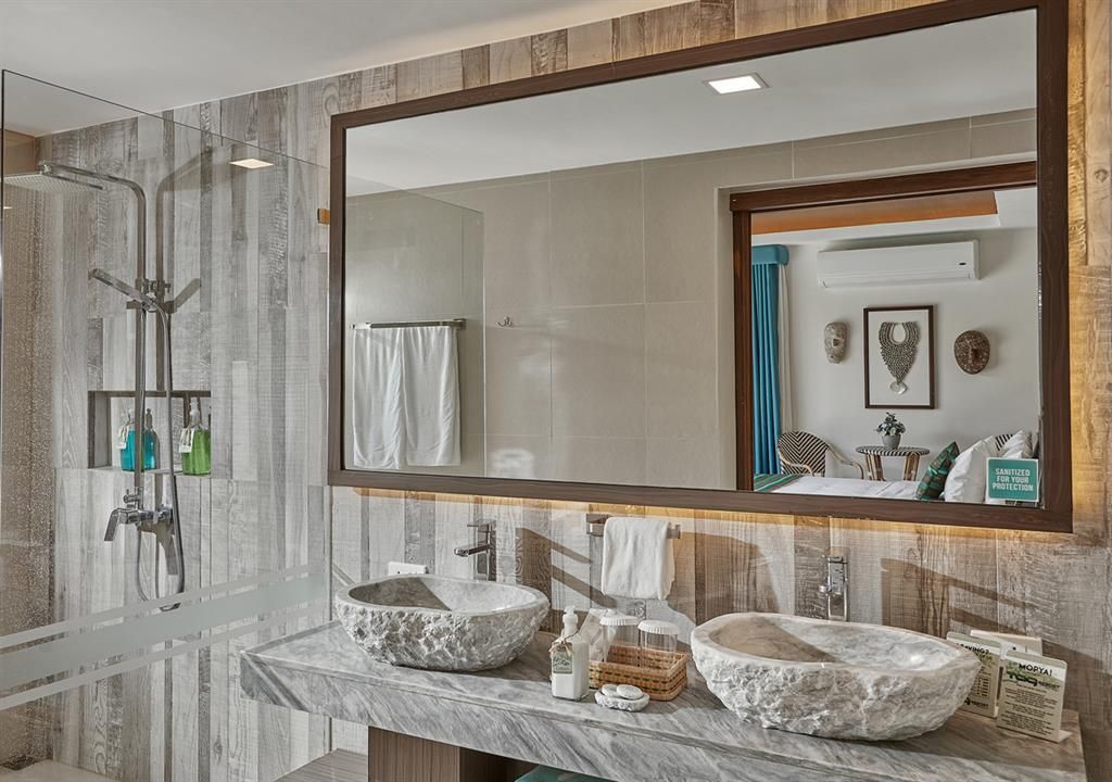Modern bathroom vanity with double sink, large mirror, and tiled shower area in neutral tones