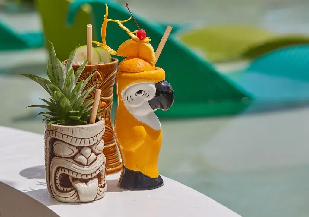 Tiny tropical drink decorations beside a small penguin figurine on a table