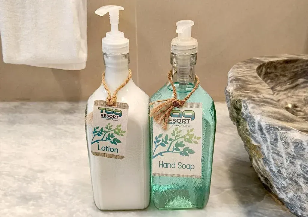 Two pump soap dispensers, one white and one turquoise, on a bathroom counter beside a sink.