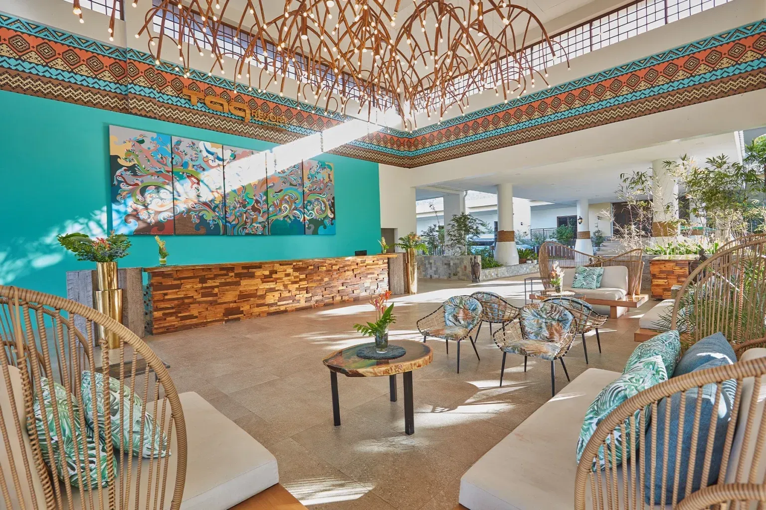 Bright tropical lounge with wicker chairs, teal accents, and open-air seating under a woven ceiling