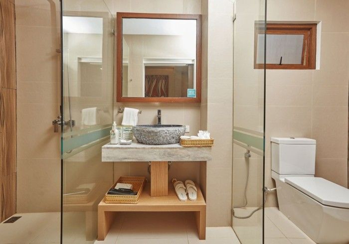 Modern bathroom with glass shower, wooden vanity, sink, and toilet