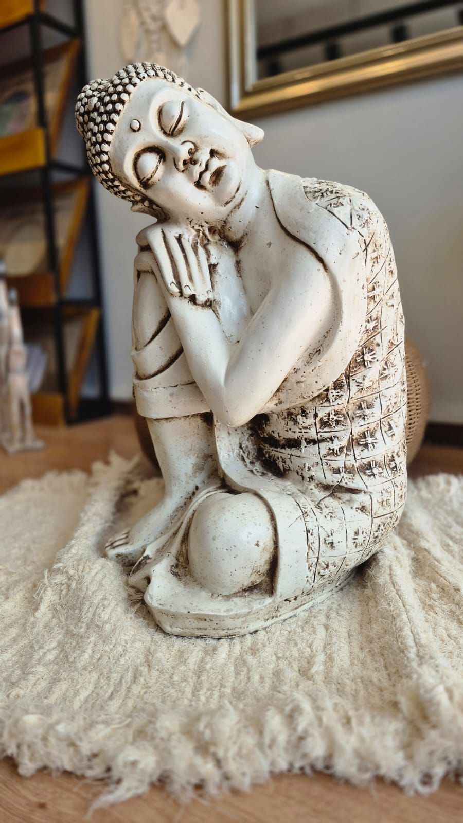 Estatua de Buda blanco recostada sobre una alfombra mullida, con los ojos cerrados y una expresión serena en el interior.