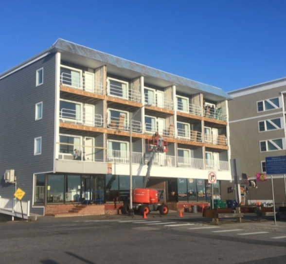 Building exterior with balconies. Construction lift in front. Blue sky overhead.