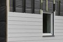 Exterior wall under construction with gray siding and window.