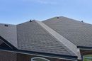 Dark gray asphalt shingle roof on a house against a blue sky.