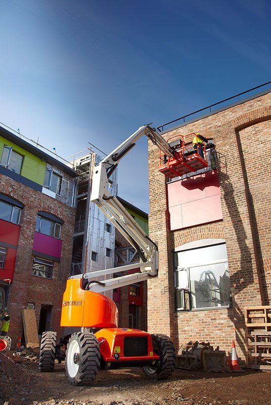 Un hombre está trabajando en un edificio con una grúa.