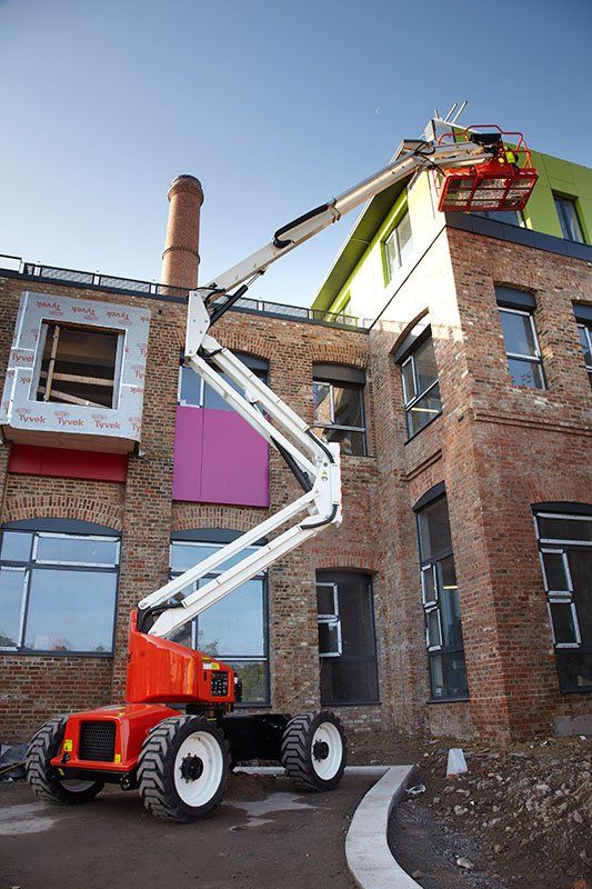 Un vehículo de construcción está estacionado frente a un edificio de ladrillo en construcción.