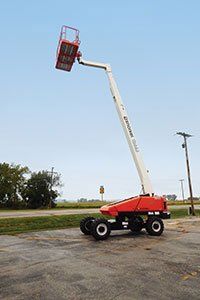 Un elevador aéreo rojo y blanco está estacionado en un estacionamiento.