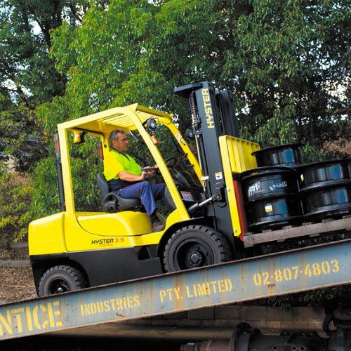 Un hombre conduce una carretilla elevadora Hyster amarilla.