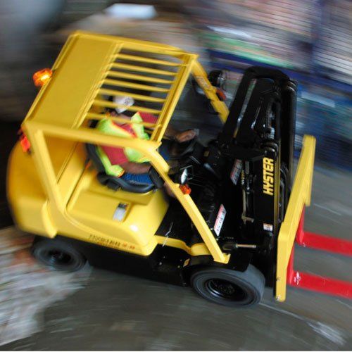 Una carretilla elevadora Hyster amarilla circula por una carretera