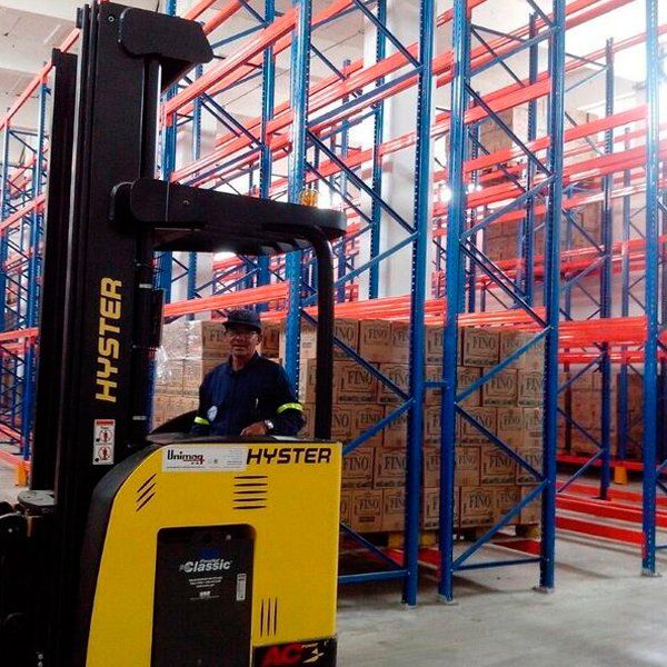 Un hombre conduce una carretilla elevadora Hyster en un almacén.