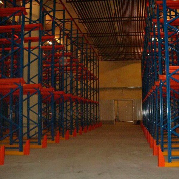 Un almacén vacío con estantes azules y naranjas.