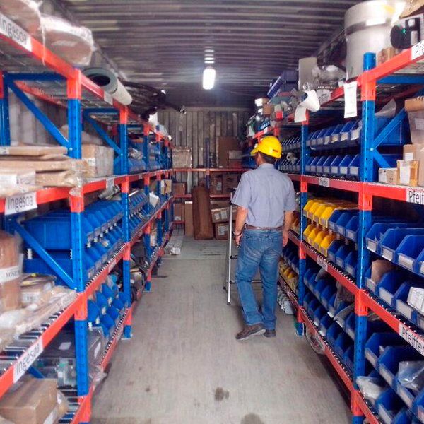 Un hombre con un casco amarillo está parado en un almacén.