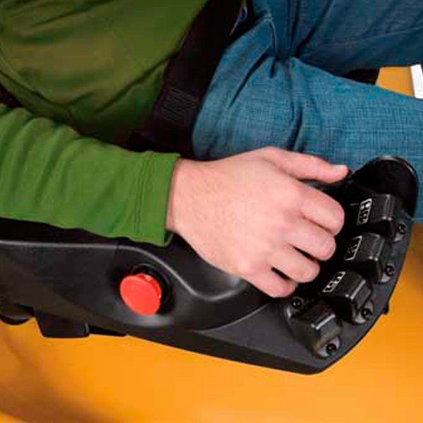 Una persona está sentada en una silla con las manos en un panel de control.